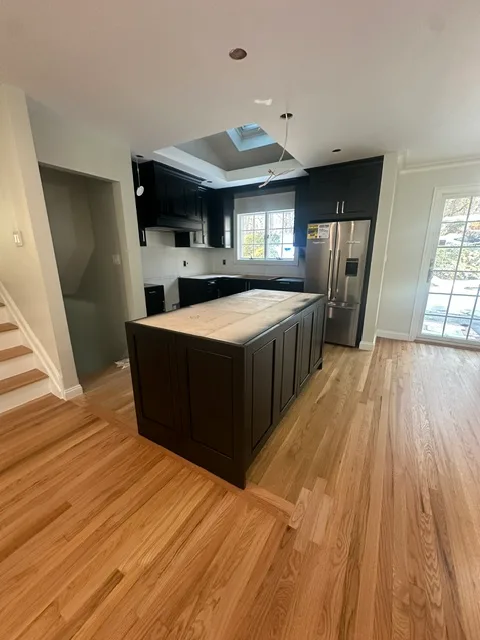 Renovated kitchen with dark island and hardwood floors