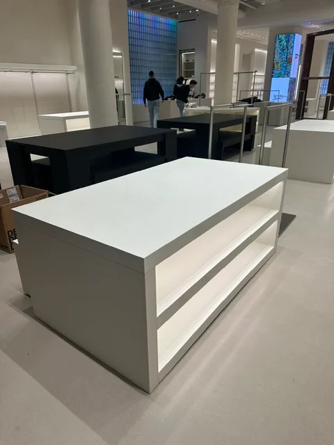 Custom white millwork display table with open shelving, retail build-out in Manhattan